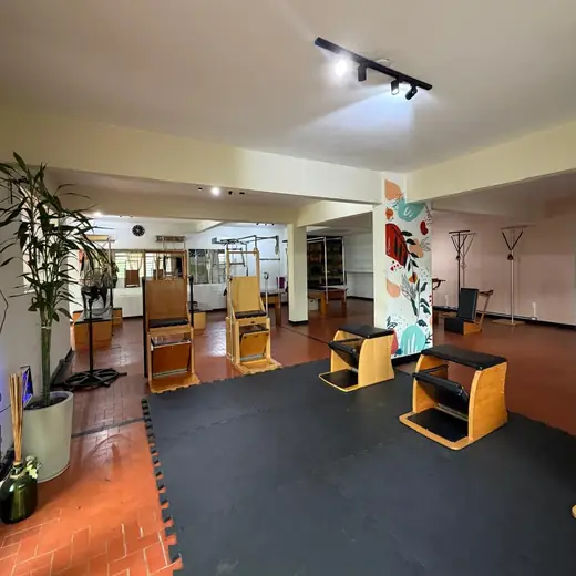 Salão do estúdio Casa Domina com aparelhos de Pilates e piso de tijolinho