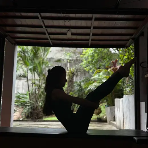 Aluna em exercício de Pilates Clássico no cadillac, com vista para o jardim