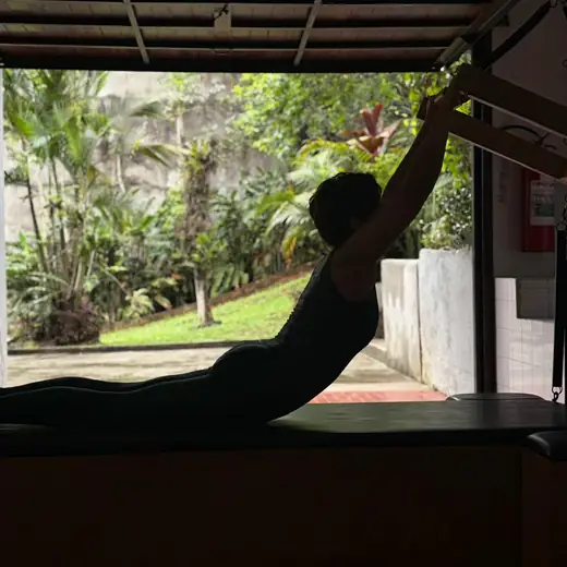Aluna em exercício de extensão no cadillac, com vista para o jardim da Casa Domina